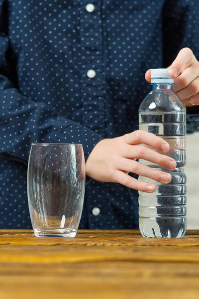 Junge öffnet Wasserflasche. Junge öffnet Flasche mit Trinkwasser — Stockfoto