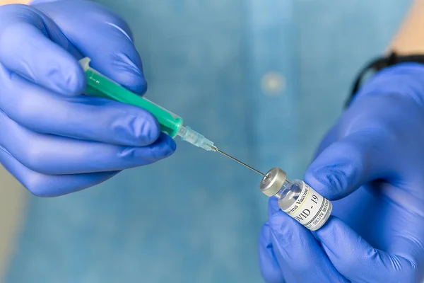 Läkaren slår in vaccinet i en spruta. en sjuksköterska med ett vaccin och en spruta i händerna — Stockfoto