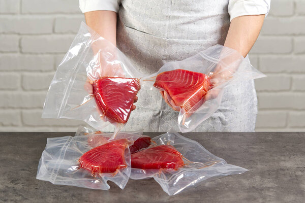 a cook or a seller at a fish market holding a bluefin tuna steak packed in a vacuum bag