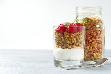 Granola ve taze yaban mersinli yoğurt ve ahududulu cam. Sağlıklı kahvaltı: granola ve böğürtlenli yoğurt