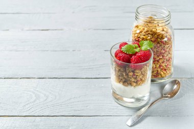 Granola ve taze yaban mersinli yoğurt ve ahududulu cam. Sağlıklı kahvaltı: granola ve böğürtlenli yoğurt