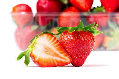 Yunanistan Çilekleri beyaz arka planda izole edilmiş. Arka planda plastik tepsiyle taze organik olgun İspanya çileği.