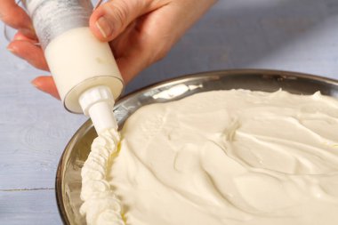 Kadın fırıncı krem şanti sıkar. Kremalı pasta ve çilekli kremadan yapılmış ev yapımı çilekli pasta..