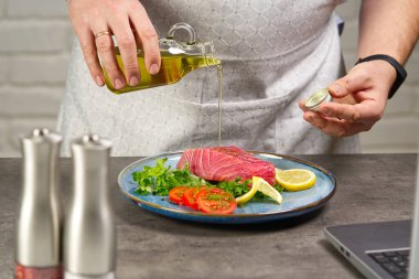 Ev mutfağında ton balığı bifteği pişirmek. Online yemek tarifi konsepti, evde balık pişirme