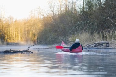 young man rowing canoe in early spring morning. lifestyle. Morning landscape, fog by the morning river and people on the canoe