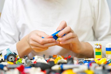 Masada renkli plastik tuğlalarla oynayan çocukların ellerini kapatın. Çocuklarda iyi motor becerilerin gelişimi, beyin aktivitelerinin gelişmesi için elverişli. Oyuncaklar geliştiriliyor