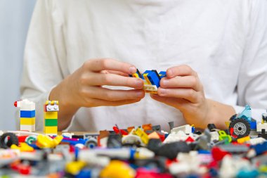 Masada renkli plastik tuğlalarla oynayan çocukların ellerini kapatın. Çocuklarda iyi motor becerilerin gelişimi, beyin aktivitelerinin gelişmesi için elverişli. Oyuncaklar geliştiriliyor