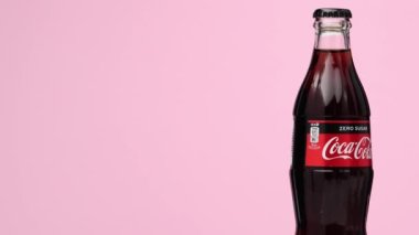 Estonya, Tallinn - Mart 2021: cam şişe coca-cola sıfır şekerli içecek izole edilmiş pembe arka planda dönüyor.