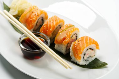 Suşi ve soya sosu beyaz kasede ve tahta çubuklar beyaz masada. Japon yemeği. Japon deniz ürünleri suşi seti. Suşi Bar Menüsü.