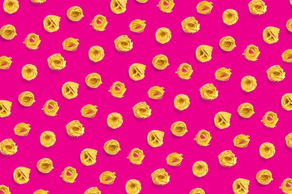 Pop art background from Italian pasta tagliatelle сира паста fettuccine pop art background, flat lay. Італійська сира паста, ізольована на рожевому. — стокове фото
