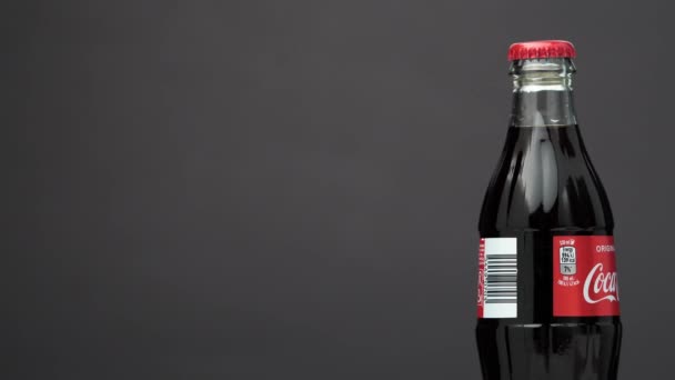 Estonsko, Talin - březen 2021: skleněná láhev coca-cola soda nápoj rotující na izolovaném tmavě černém pozadí. — Stock video