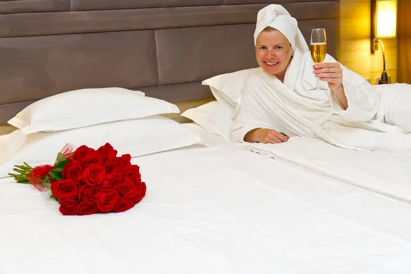 woman in hotel room with bouquet of red roses. romantic meeting of guests at the hotel.