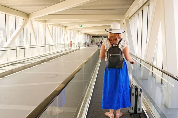 Mladá čtyřicátnice nemá obličej s kufříkem na eskalátoru na letištním terminálu. Bezpečnost cestování sám Covid-19 čas — Stock fotografie