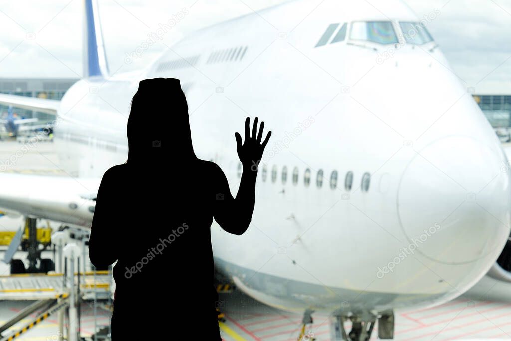 Black woman silhouette looking to aircraft in the airport hall- missed or cancelled flight concept.