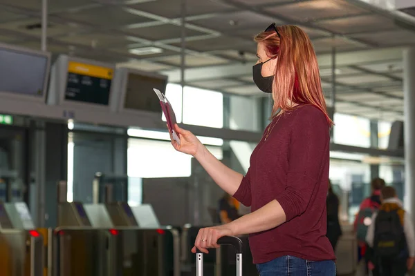 Junge Frau mit Mundschutz, Reisepass und Flugtickets am internationalen Flughafen — Stockfoto