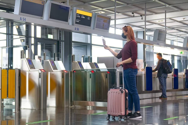 Junge Frau mit Mundschutz, Reisepass und Flugtickets am internationalen Flughafen — Stockfoto