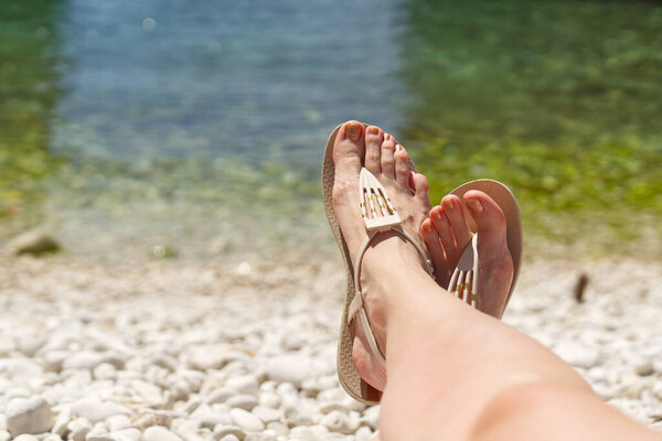 beautiful legs on a rocky beach. woman feet on front of sea rocky beach.