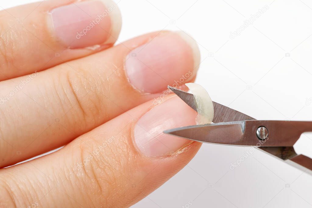 Home nail care. A girl cuts a fragile broken nail. Brittle nail concept