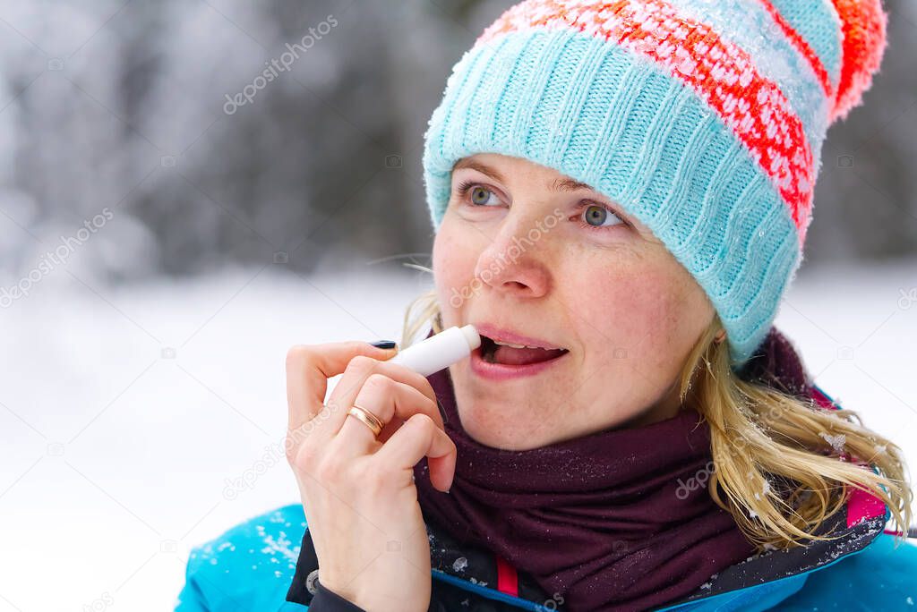 girls uses hygienic lipstick outside in winter in frost. lip care on frosty days