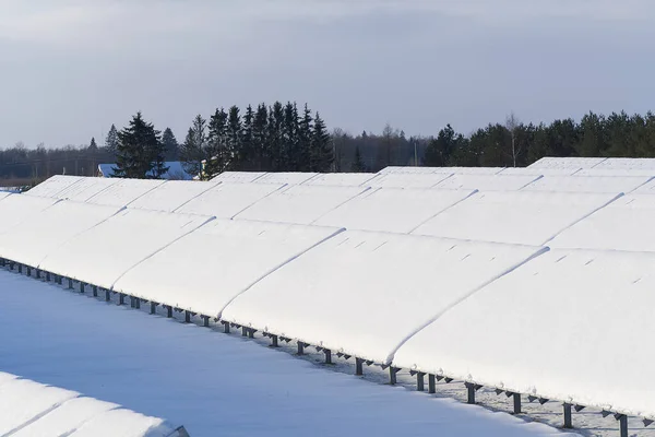 Solar panel field covered with snow. renewable energy in winter low efficiency. renewable green energy industry concept in winter time.
