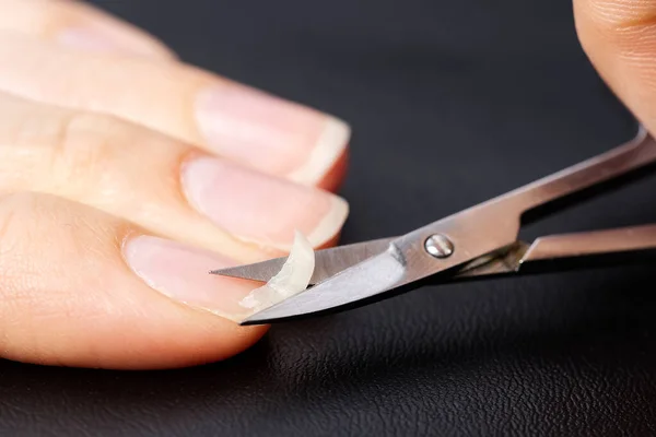 Cuidado casero de uñas. Una chica corta un frágil clavo roto. concepto de uñas frágiles — Foto de Stock