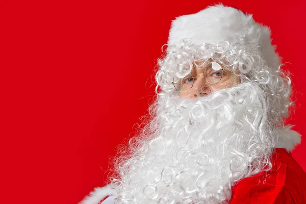 Retrato de un hombre vestido de santa claus sobre un fondo rojo — Foto de Stock