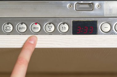 Kadınlar bulaşık makinesinin paneline su ve elektrik tasarrufu için bir ekolojik program kuruyor.