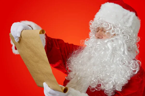 Santa Claus holding blank brown scroll paper. Christmas holiday wish list concept mockup — Stock Photo, Image