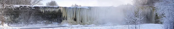 Frozen beautiful waterfall Jagala under the sunrise lights in winter, reflection in river. Estonia. — Stock Photo, Image