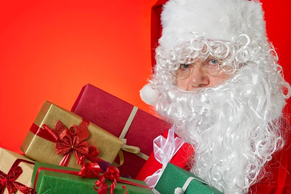 Szczęśliwy Święty Mikołaj z pudełek w rękach na czerwonym tle z miejsca do kopiowania — Zdjęcie stockowe