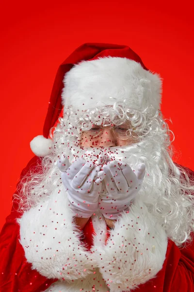 Weihnachtsmann bläst rotes Glitzerkonfetti aus den Händen — Stockfoto