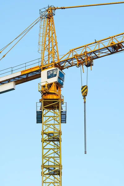 Construction tower crane on blue sky background. Yellow tower crane. Industrial construction crane
