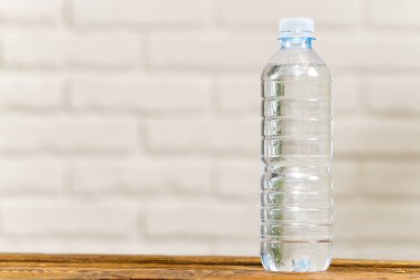 Tahta masada ve beyaz duvarda plastik şişede su içmek. Sağlık konsepti. Boşluğu kopyala