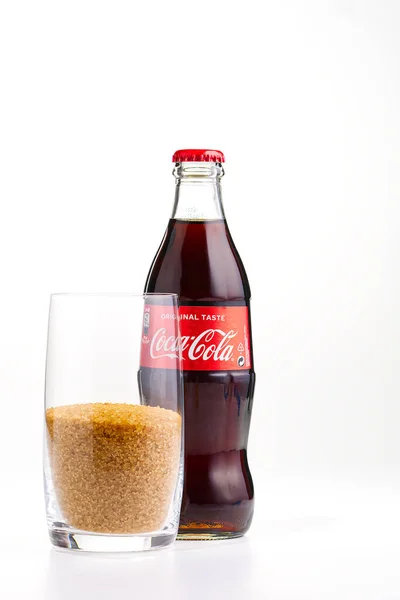 Tallinn, Észtország - 12.02.21. Egy üveg Coca Cola üdítőt. Egy üveg CocaCola és Glass barna cukorral. az ital cukortartalmának illusztrációja. — Stock Fotó