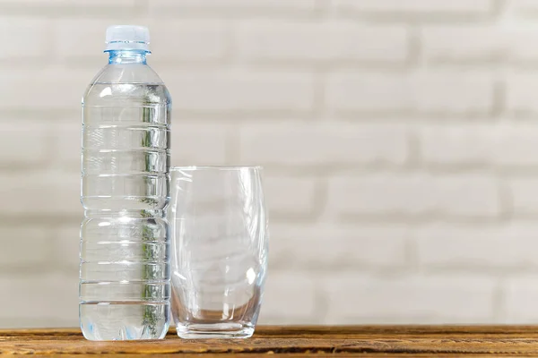 Drinking water in plastic bottle on wooden table and white wall. Health concept. copy space