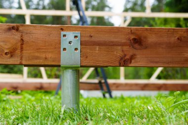 Güverte inşaatı için kereste iskelesi destekleyen bir vida vakfının yakın çekimi. Bu sistem dayanıklılık ve istikrar sunarak, açık alanlar ve peyzaj için ideal hale getiriyor..