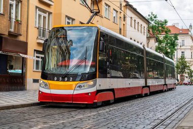 Çek Cumhuriyeti 'nin Prag kentindeki bir kaldırım taşı caddesinde modern bir tramvay süzülüyor ve tarihi mimariyle şık bir şekilde birleşiyor. Seyahat broşürleri ve verimli şehir ulaşımı için ideal.