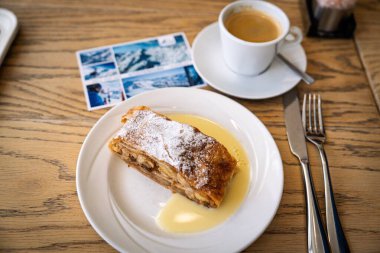 Güzel Avusturya Alplerinde vanilya sosuyla servis edilen pudra şekerli geleneksel elmalı turtanın tadını çıkarın, Kaprun. Kahveyle harika gider..