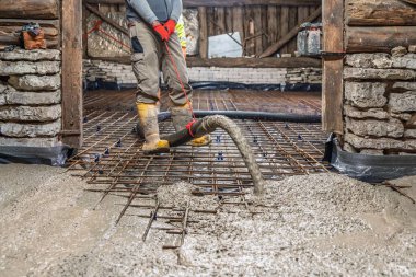 Bir inşaat işçisi yoğun bir alana beton dökerek demir takviyesi yapıyor. Bu adım, yeni proje için güçlü ve kalıcı bir temel oluşturmak için hayati önem taşıyor..