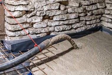 Bodruma beton pompalanarak sağlam bir zemin için taş duvarlar oluşturuluyor. Yenileme projeleri ve ev geliştirme kavramları için ideal, modern materyallerin ve yapısal bütünlüğün sergilenmesi.