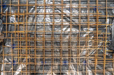 Beton dökülmesi için hazırlanan siyah plastik çarşaflara dayanan takviye demiri şebekesi. Bu çerçeve inşaat projelerinde yapısal bütünlük için gereklidir..