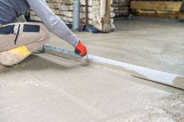 Bir inşaat işçisi ustalıkla pürüzsüz taze betonu düzleştirerek düz bir yüzey oluşturur. Bu görüntü, kalifiye işçiliğin ve ev yenilemenin özünü yansıtıyor..