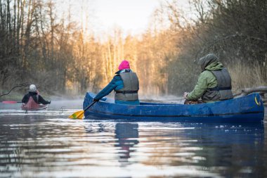 Sakin bir nehirde kano süren insanlar gibi sisli bir sabah yaşayın. Açık hava maceraları veya eko-turizmi için idealdir, bu görüntü rahatlamayı ve aktif bir yaşam tarzını yakalar.