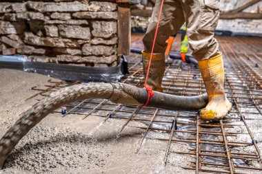 Bir inşaat işçisi, destek ağıyla beton döker. Bu resim sağlam temeller inşa etmek için kullanılan temel inşaat tekniklerini gösteriyor.