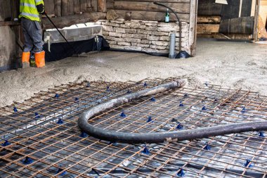 İnşaat işçisi takviye şebekesine taze beton döşeyerek temel inşa etmek için sağlam bir taban sağlıyor. Dayanıklı yapılar oluşturmada, kalite ve güce odaklanmada hayati bir adım.