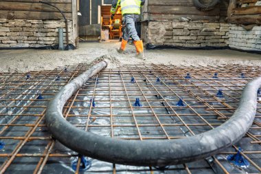 Bir inşaat işçisi binanın içinde güçlü bir levha oluşturmak için beton döker. Demir takviyesi istikrar için kullanılır. Bu resim inşaat ve mühendislik temaları için idealdir.