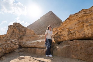 Mısır 'daki Giza Piramidi yakınlarındaki kaya oluşumları arasında bir kadın, turizm, seyahat deneyimleri, başyazı ve macera konsepti için antik mimari ve kültür mirasını sergiliyor..