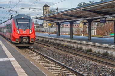 Almanya, 20.12.2025 - Almanya 'da verimli ulaşım gösteren modern kırmızı bir DB treni istasyona ulaşır. Seyahat günlükleri ve tanıtım içeriği için ideal.