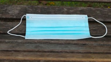 Mavi tek kullanımlık koruyucu maske, Cornavirus 'a karşı korunmak için kullanılır, Rio de Janeiro' da ahşap bir bankta fırlatılır..