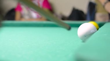 Adam bilardo oynuyor, beyaz topa vuruyor..